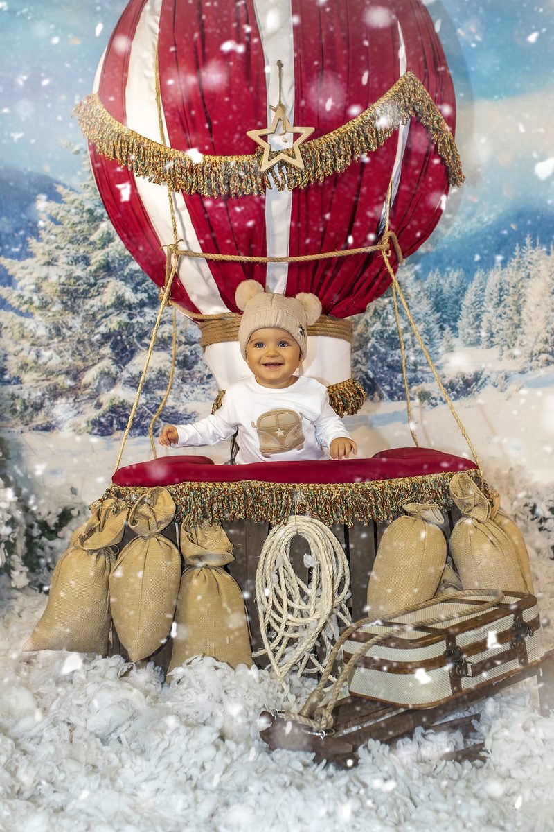 Niña en la cesta del globo aerostático con nieve en la campaña de Navidad de Murcia