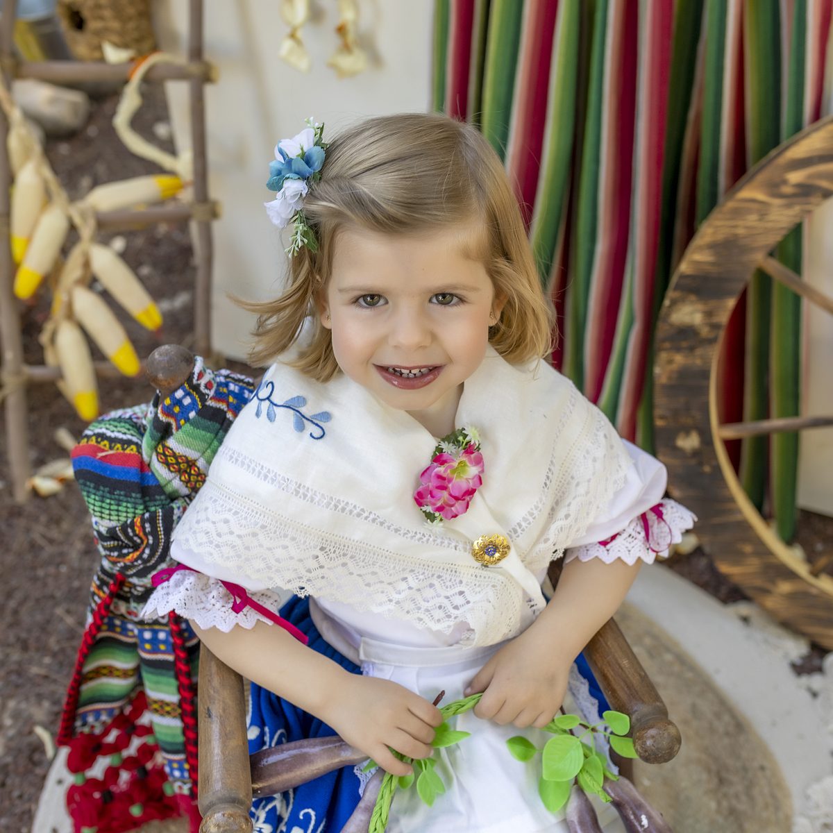 Niña de huertana sentada en la mecedora del decorado huertano de Murcia