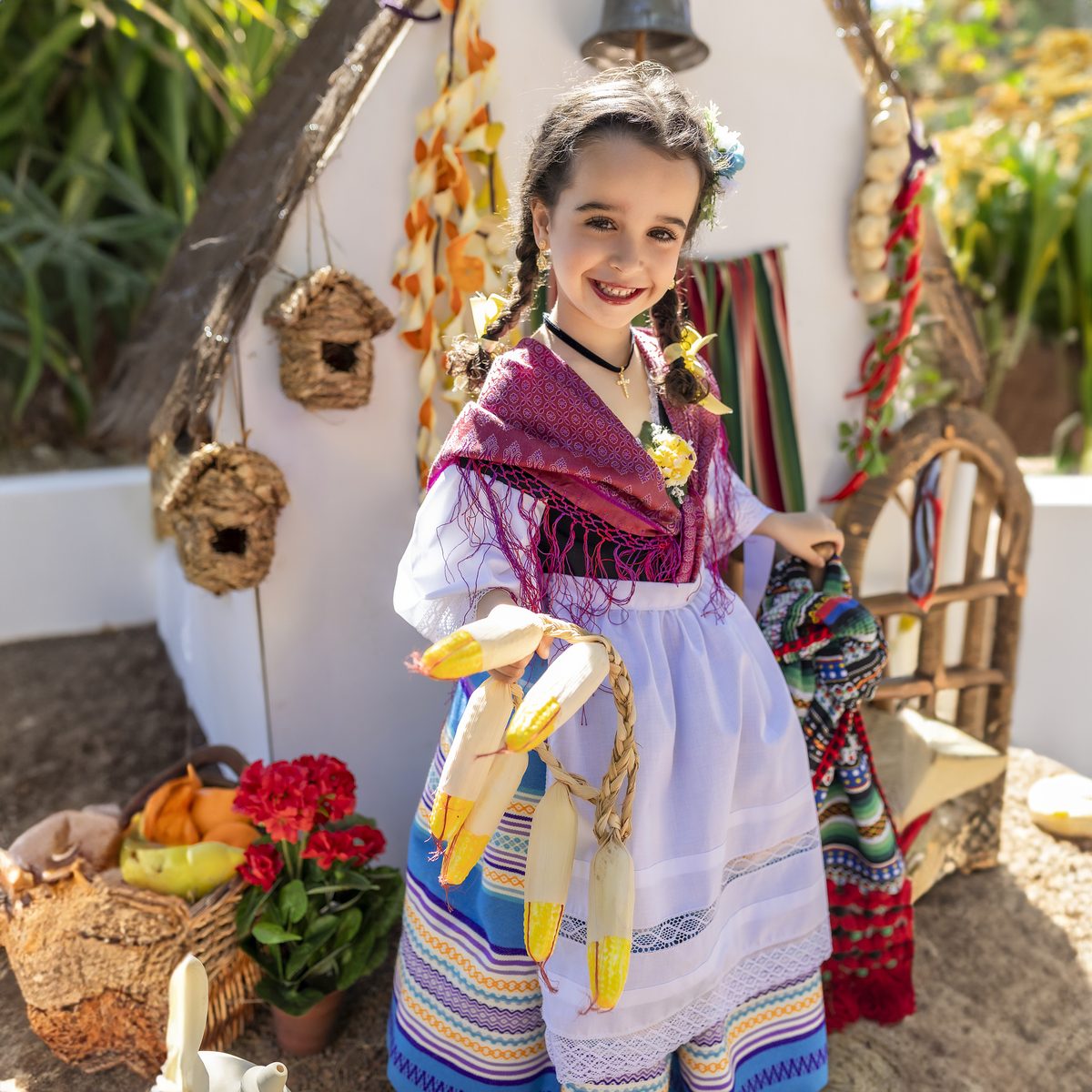 Niña con traje de huertana entre macetas y flores de la huerta murciana