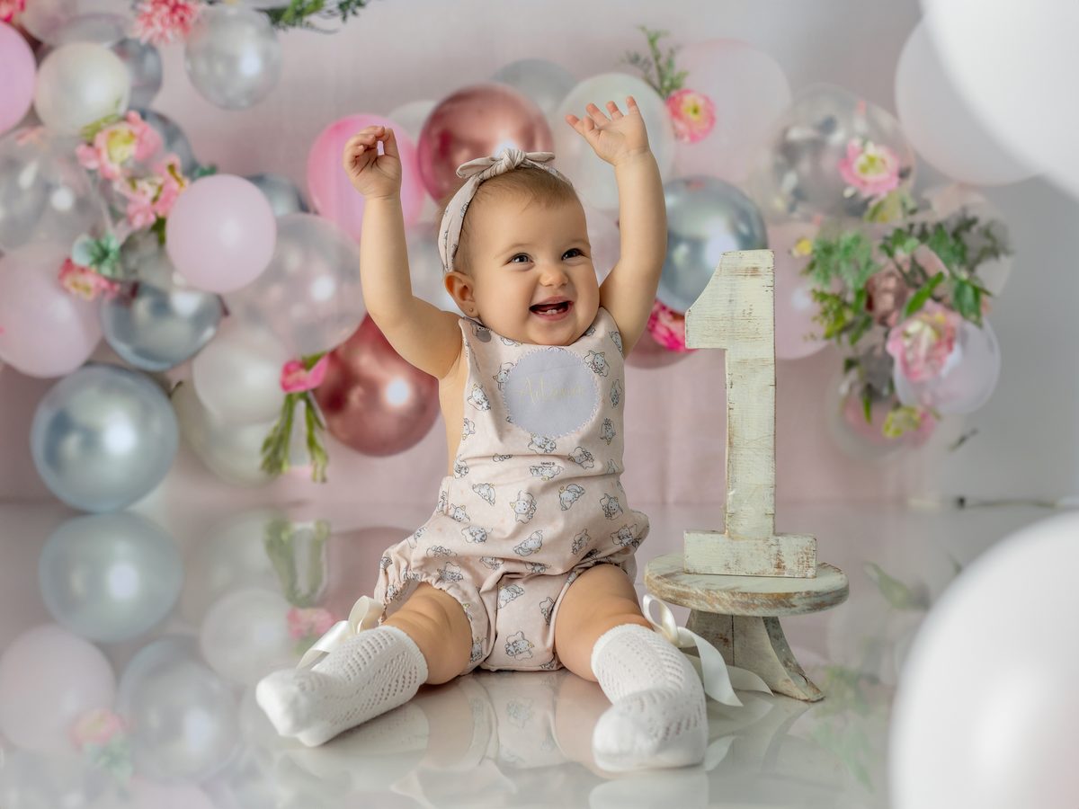 Bebé sonriendo con globos y el letrero ONE en su primer cumpleaños en Murcia