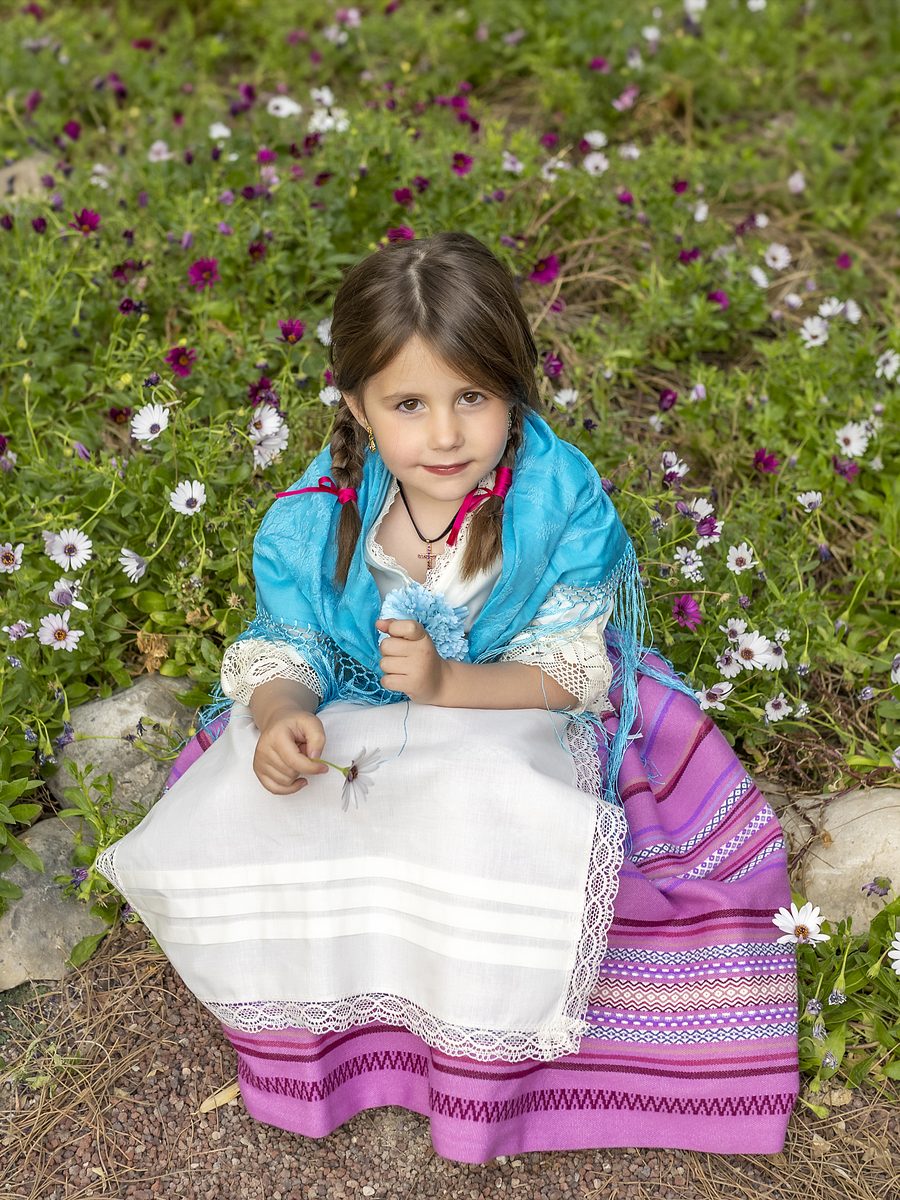 Niña con traje de huertana en un campo de margaritas en la campaña de Primavera de Murcia