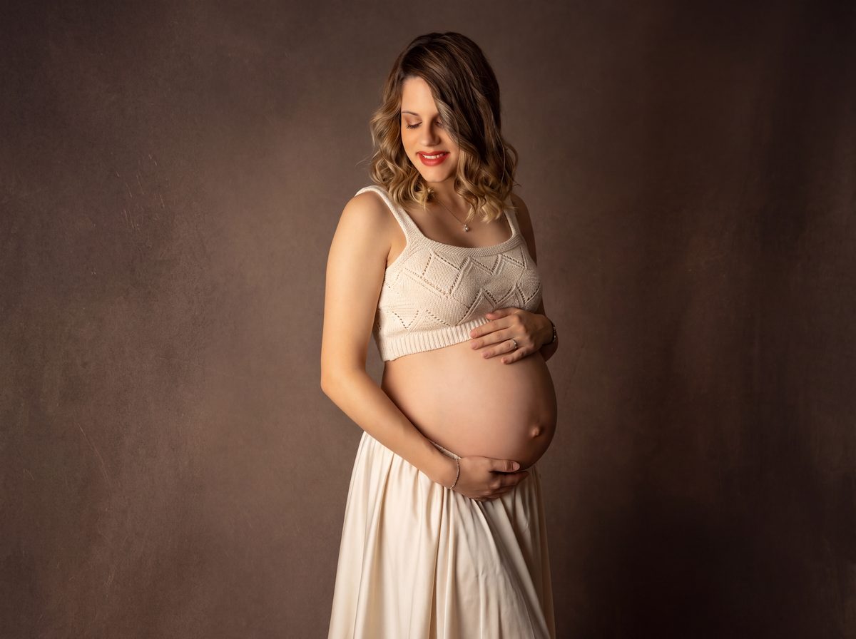 Embarazada con vestido beige acariciando su barriga en Murcia